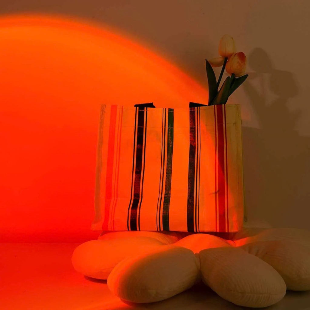 Lampe coucher de soleil SUNSET créant une ambiance rouge sur des vases et coussins