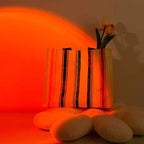 Lampe coucher de soleil SUNSET créant une ambiance rouge sur des vases et coussins