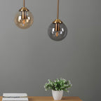 Suspensions LUNA en verre ambre et gris fumé allumées dans un intérieur moderne