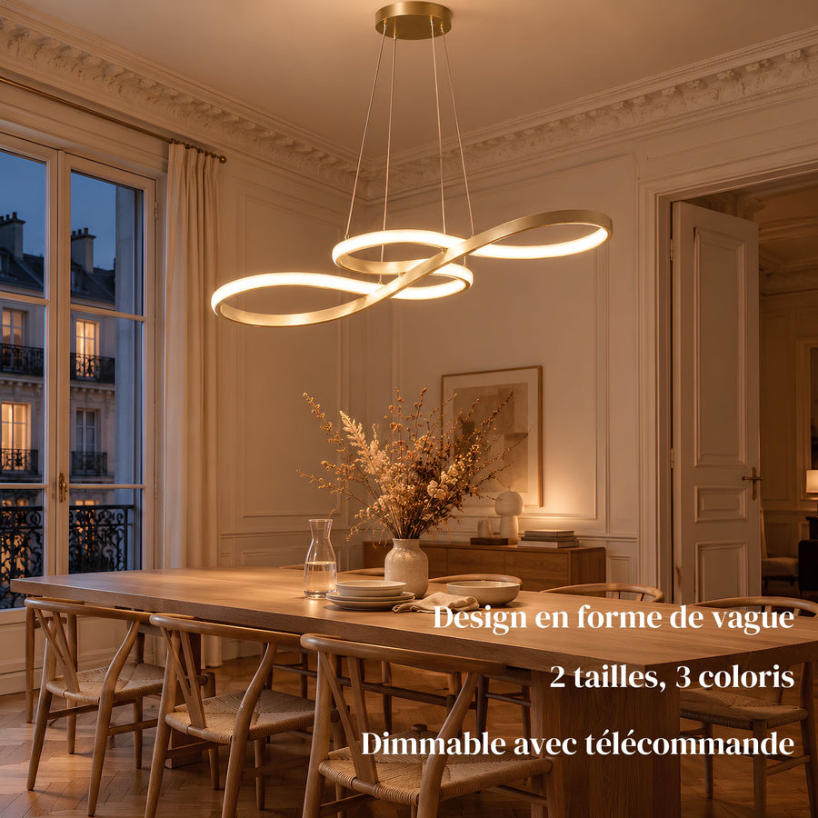 Suspension LED ONDA dorée allumée au-dessus d'une table de salle à manger en bois